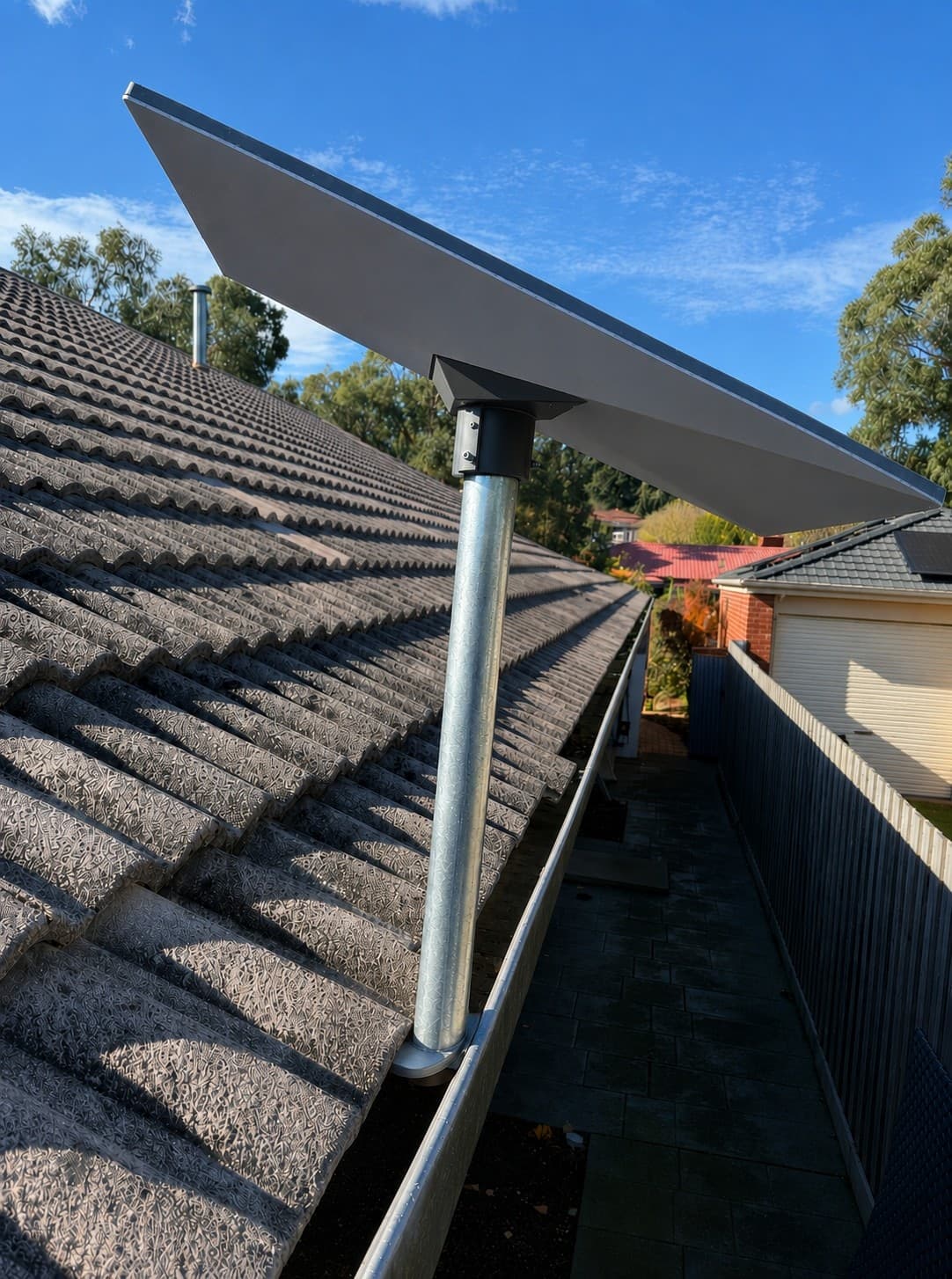 Starlink mast fitted beside a tile roof